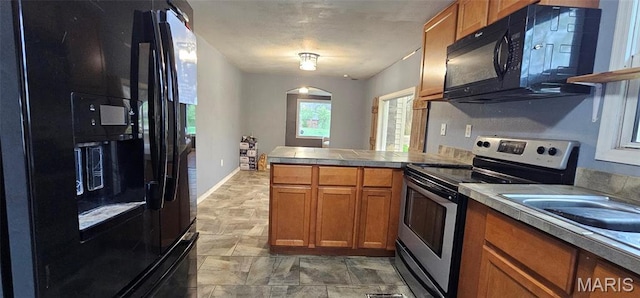 12753 Hencher Rd, De Soto, MO 63020 - kitchen featuring black appliances, brown cabinets, a peninsula, arched walkways, and light countertops