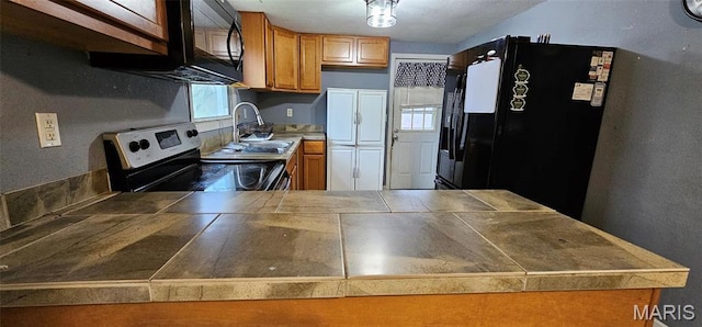 12753 Hencher Rd, De Soto, MO 63020 - kitchen with black appliances, a sink, a peninsula, brown cabinetry, and tile countertops