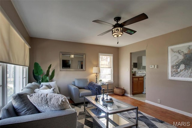 902 E Morgan St, Edina, MO 63537 - living room featuring a ceiling fan, light wood-style floors, baseboards, and a baseboard heating unit