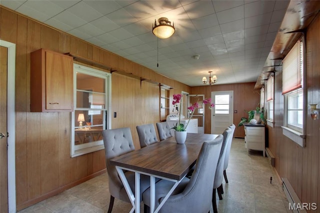 902 E Morgan St, Edina, MO 63537 - dining area with wooden walls, a baseboard radiator, a chandelier, baseboards, and washer / clothes dryer