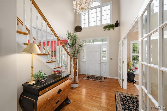 1114 Lockett Rd, Des Peres, MO 63131 - entrance foyer with stairway, light wood finished floors, a high ceiling, a chandelier, and baseboards