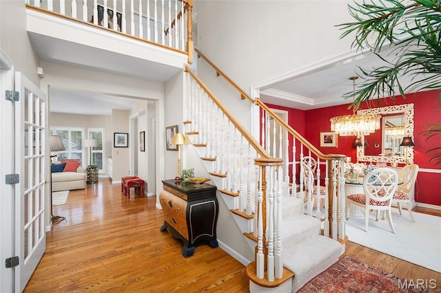 1114 Lockett Rd, Des Peres, MO 63131 - staircase featuring wood finished floors, a chandelier, french doors, a high ceiling, and baseboards