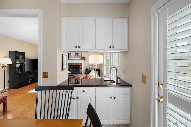 1114 Lockett Rd, Des Peres, MO 63131 - kitchen with a sink, a brick fireplace, white cabinetry, and dark countertops