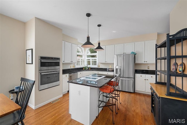 1114 Lockett Rd, Des Peres, MO 63131 - kitchen with appliances with stainless steel finishes, white cabinetry, decorative light fixtures, and a center island