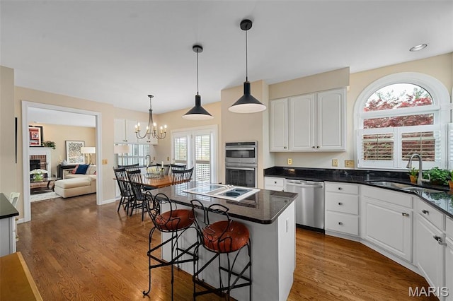 1114 Lockett Rd, Des Peres, MO 63131 - kitchen with stainless steel appliances, a kitchen bar, white cabinetry, wood finished floors, and a sink