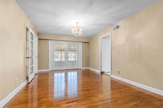 605 W Washington St, Kennett, MO 63857 - spare room featuring french doors, a chandelier, wood finished floors, and baseboards