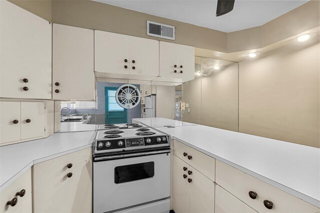 605 W Washington St, Kennett, MO 63857 - kitchen featuring electric stove, light countertops, white cabinets, and a sink