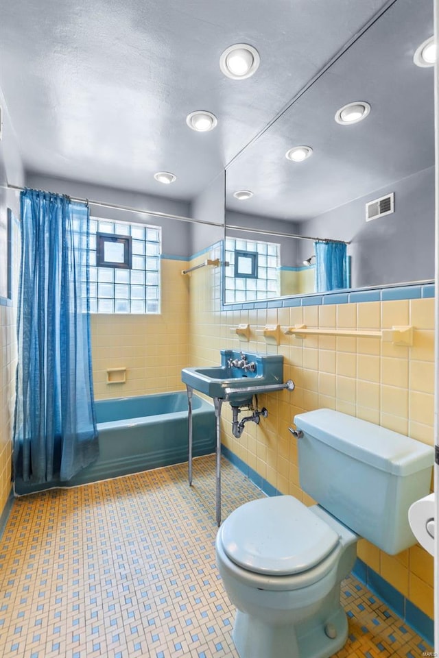 605 W Washington St, Kennett, MO 63857 - full bathroom with tile walls, toilet, shower / bath combo with shower curtain, and recessed lighting