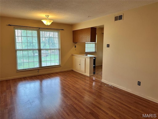8736 Santa Bella Dr Unit G, Hazelwood, MO 63042 - unfurnished dining area featuring dark wood-style floors, a textured ceiling, and baseboards