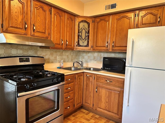 8736 Santa Bella Dr Unit G, Hazelwood, MO 63042 - kitchen featuring freestanding refrigerator, stainless steel range with gas stovetop, under cabinet range hood, a sink, and black microwave