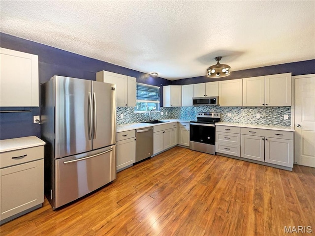 1 Pine Forest Ct, Dardenne Prairie, MO 63368 - kitchen featuring stainless steel appliances, a sink, wood finished floors, decorative backsplash, and a textured ceiling