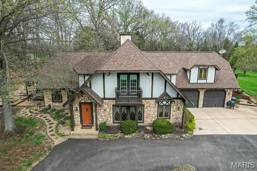 762 Crider Ln, Union, MO 63084 - tudor-style house featuring stone siding, driveway, a balcony, and stucco siding