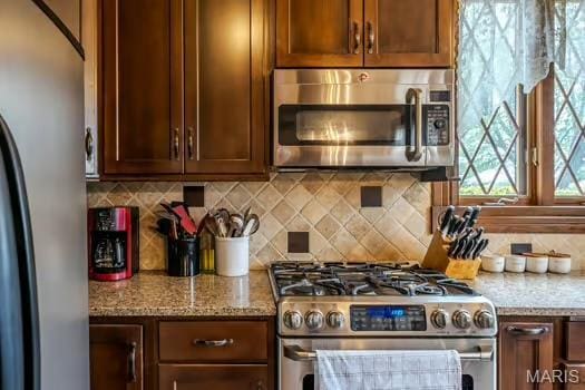 762 Crider Ln, Union, MO 63084 - kitchen featuring appliances with stainless steel finishes, decorative backsplash, and light stone countertops