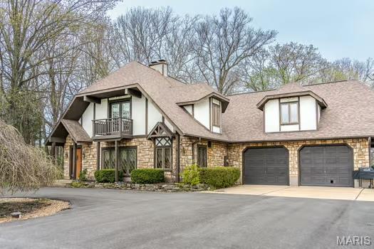 762 Crider Ln, Union, MO 63084 - view of front of property with a balcony, stone siding, driveway, a chimney, and a shingled roof