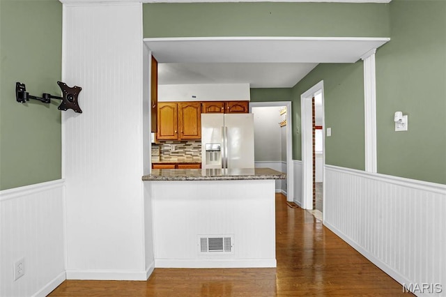 765 Pottery Tower Ln, Washington, MO 63090 - kitchen with fridge with ice dispenser, a peninsula, dark wood-style floors, brown cabinets, and a wainscoted wall