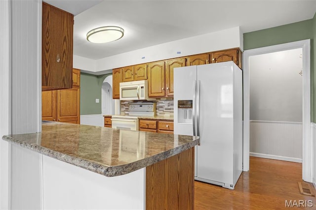 765 Pottery Tower Ln, Washington, MO 63090 - kitchen featuring white appliances, light wood-style flooring, a peninsula, arched walkways, and decorative backsplash