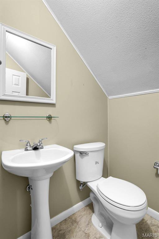 765 Pottery Tower Ln, Washington, MO 63090 - bathroom featuring baseboards, toilet, vaulted ceiling, a sink, and a textured ceiling