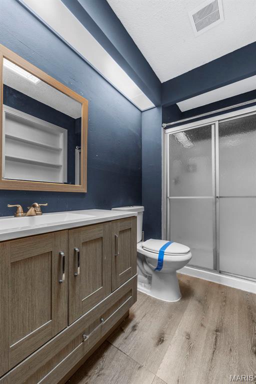 1064 Pinecone Trl, Florissant, MO 63031 - bathroom with vanity, wood finished floors, toilet, and a shower stall