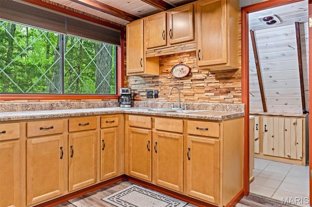 kitchen featuring a sink, backsplash, healthy amount of natural light, light countertops, and wood ceiling