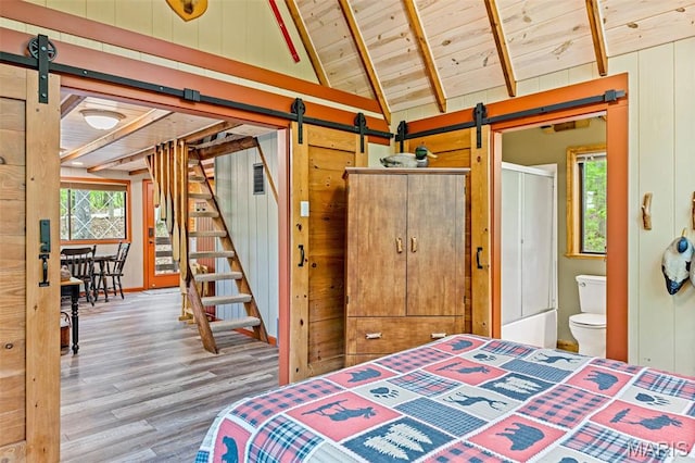 bedroom featuring a barn door, wood finished floors, wooden ceiling, and wood walls