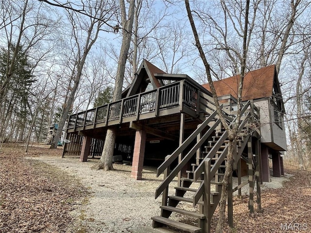 view of side of home with a deck, stairs, and a shingled roof