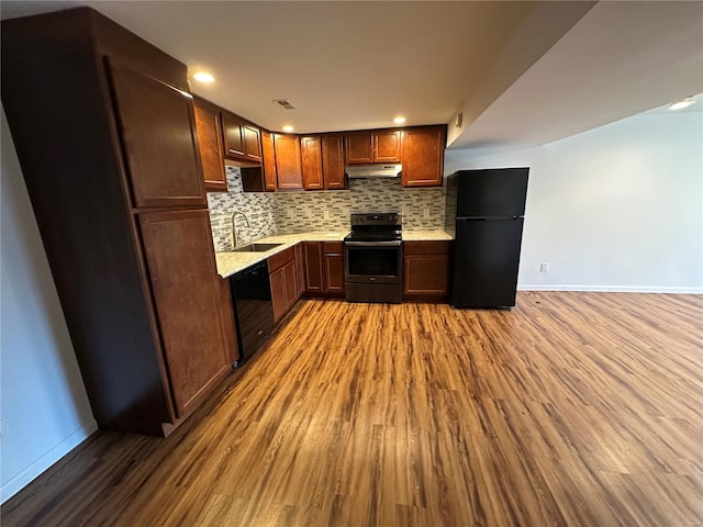 1612 California Ave, Collinsville, IL 62234 - kitchen with black appliances, under cabinet range hood, a sink, wood finished floors, and baseboards