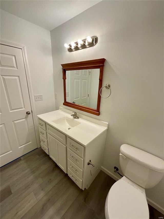 1612 California Ave, Collinsville, IL 62234 - bathroom featuring wood finished floors, toilet, vanity, and baseboards