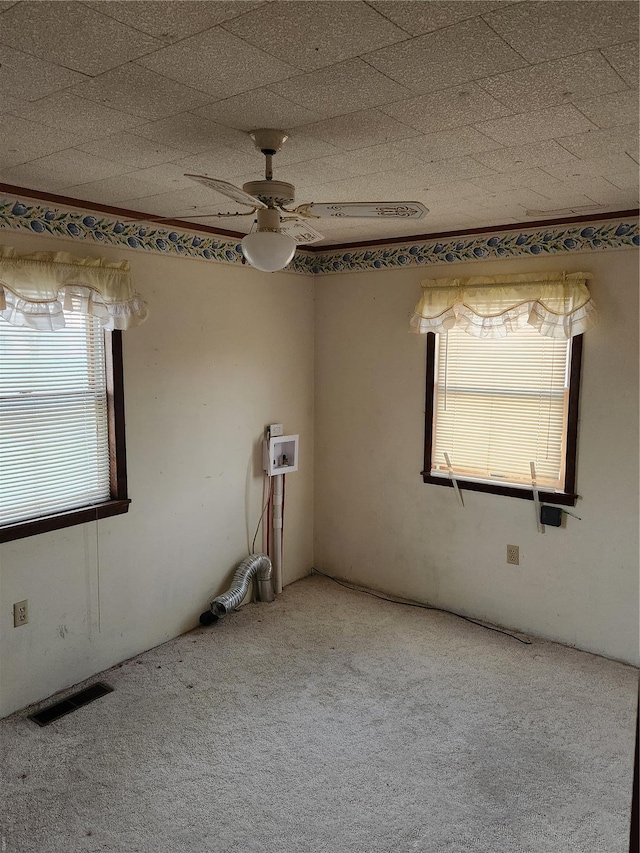 carpeted spare room featuring plenty of natural light and a ceiling fan