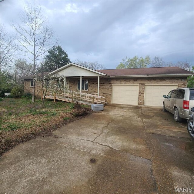 23026 Reporter Rd, Waynesville, MO 65583 - single story home featuring a garage, concrete driveway, a porch, and brick siding