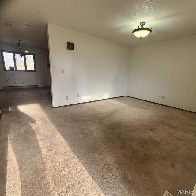 23026 Reporter Rd, Waynesville, MO 65583 - carpeted spare room featuring baseboard heating, baseboards, a chandelier, and a textured ceiling