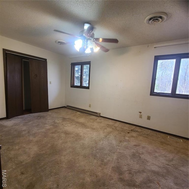23026 Reporter Rd, Waynesville, MO 65583 - unfurnished bedroom featuring baseboard heating, a textured ceiling, carpet flooring, a ceiling fan, and baseboards