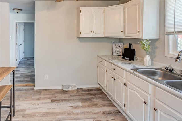 1810 N Van Buren St, Litchfield, IL 62056 - kitchen featuring white cabinetry, light wood-style flooring, a sink, light countertops, and baseboards