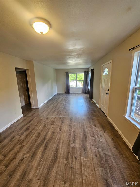 7200 Sapphire Ave, Saint Louis, MO 63136 - unfurnished living room with dark wood-style flooring and baseboards