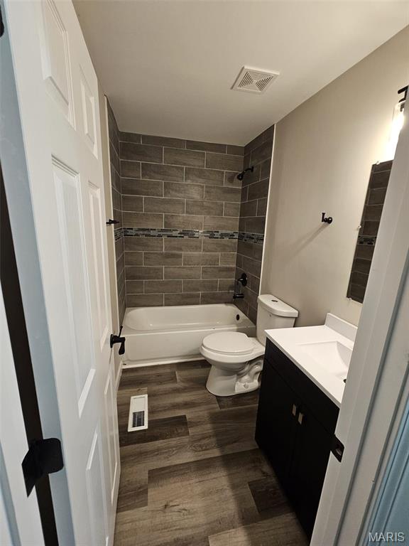 9827 Winkler Dr, Saint Louis, MO 63136 - full bath featuring toilet, wood finished floors, tub / shower combination, and vanity
