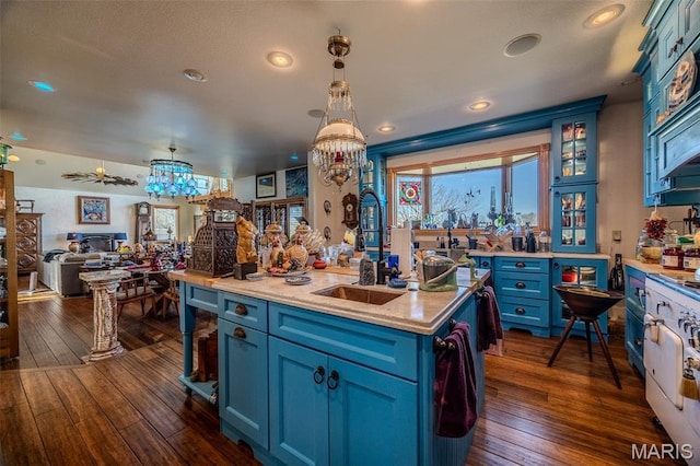 20955 Rye Ln, Richland, MO 65556 - kitchen featuring blue cabinets, a kitchen island with sink, open floor plan, dark wood-style floors, and decorative light fixtures