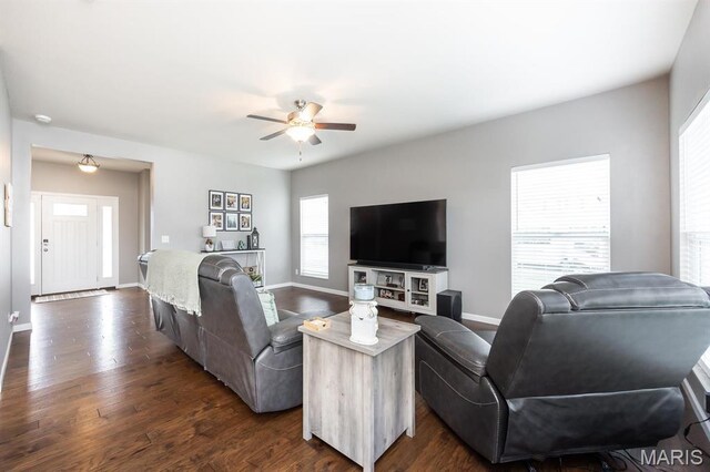 living area featuring dark wood-style flooring, a ceiling fan, and baseboards