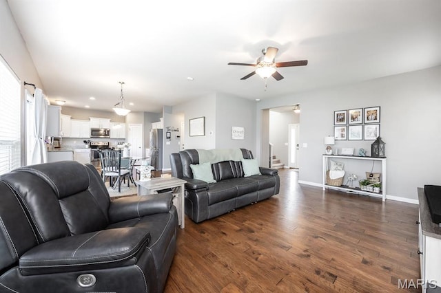 living area featuring a ceiling fan, dark wood-type flooring, stairway, and baseboards
