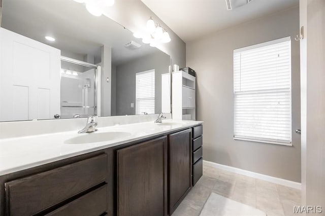 bathroom featuring baseboards, double vanity, and a shower with shower door
