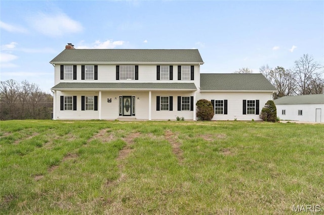 colonial inspired home with a chimney and a front lawn
