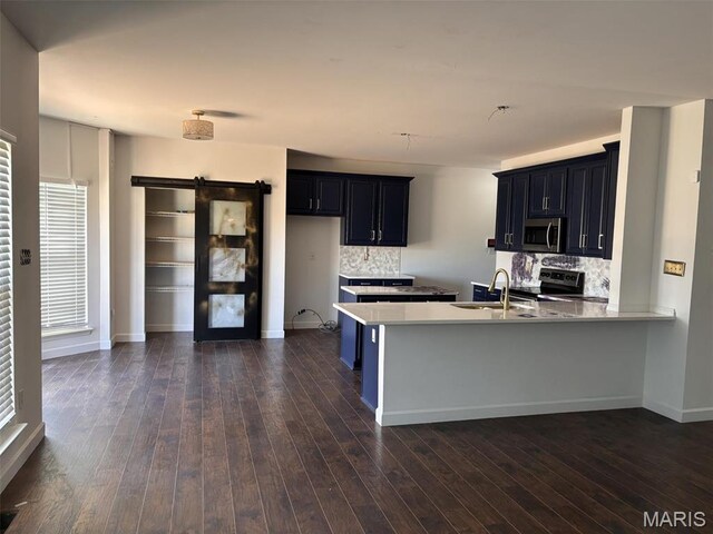 202 Reliance Rd, Foristell, MO 63385 - kitchen featuring stainless steel microwave, a sink, a peninsula, a barn door, and backsplash