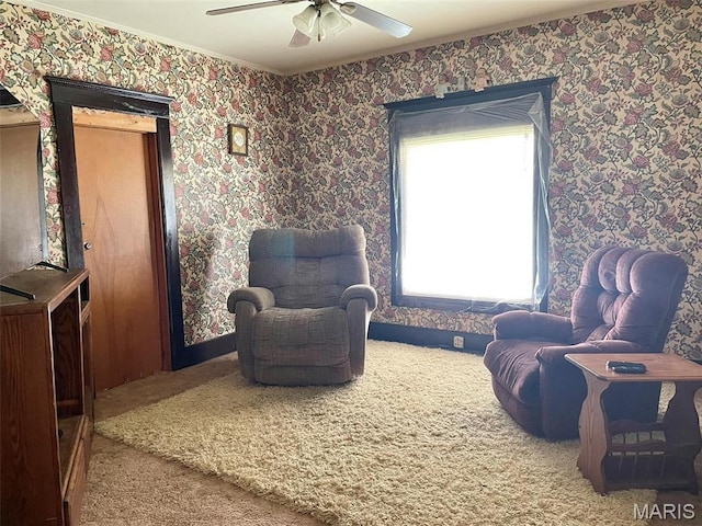sitting room with carpet, a ceiling fan, wallpapered walls, and ornamental molding