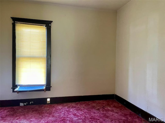 spare room featuring dark carpet and baseboards