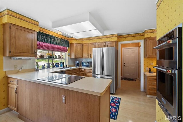 405 Seven Gables Ct, Chesterfield, MO 63017 - kitchen with stainless steel appliances, light countertops, a peninsula, light wood finished floors, and a sink