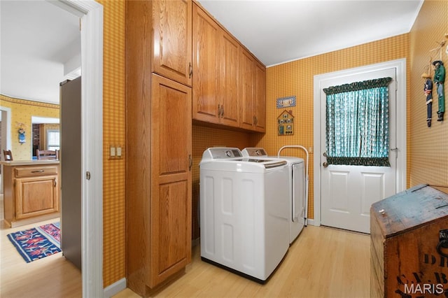 405 Seven Gables Ct, Chesterfield, MO 63017 - laundry room featuring wallpapered walls, light wood finished floors, washing machine and dryer, and cabinet space
