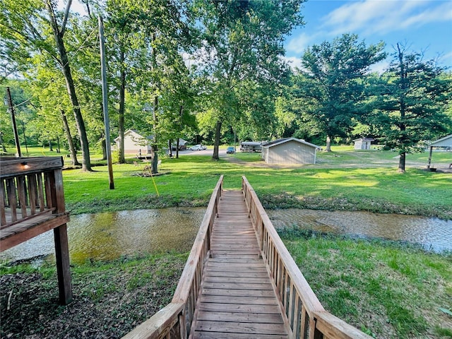 dock with a yard, a water view, and view of scattered trees