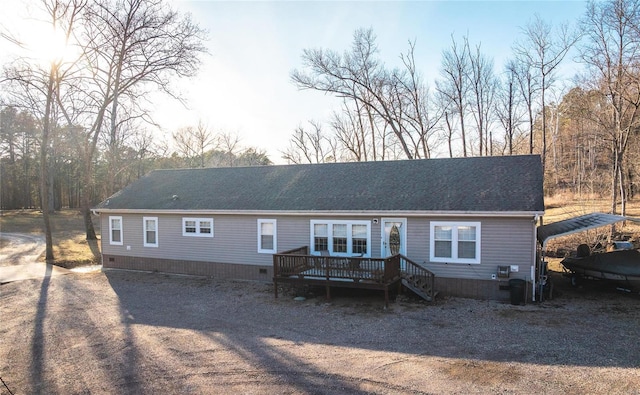 rear view of property with crawl space, a wooden deck, and a shingled roof