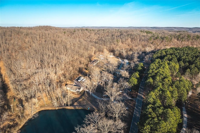 aerial view of property and surrounding area featuring a forest and a nearby body of water