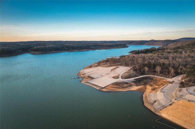 aerial view at dusk of a water view and a wooded view