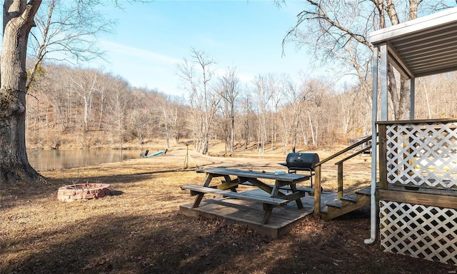 view of yard featuring an outdoor fire pit, a water view, and a forest view