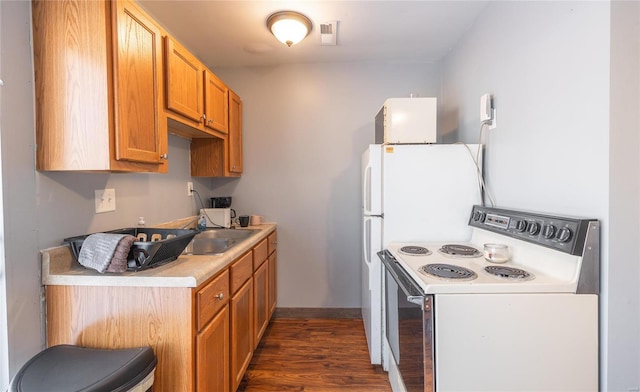 kitchen featuring electric range, dark wood finished floors, a sink, light countertops, and brown cabinetry